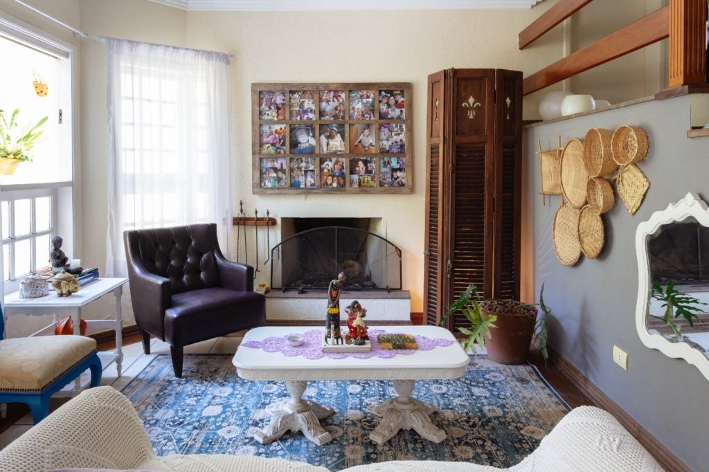 Espaço da casa, com uma linda folha de janela de madeira utilizada como porta retrados, sobre a lareira.