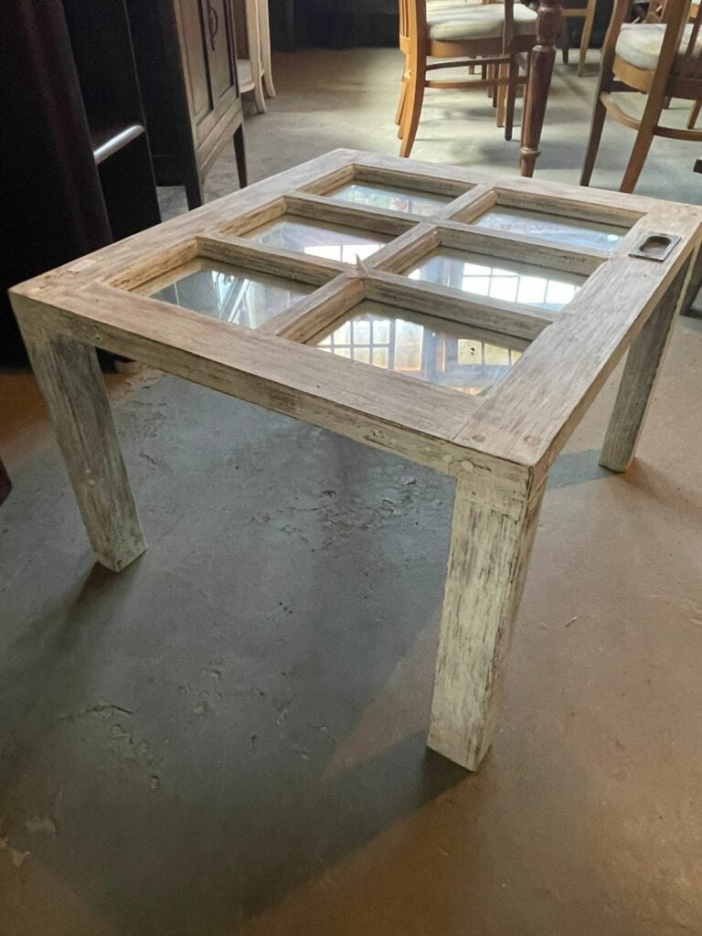 Mesa de centro feita a partir de folha de janela antiga de madeira com vidros, exemplo de reaproveitamento de demolição.
