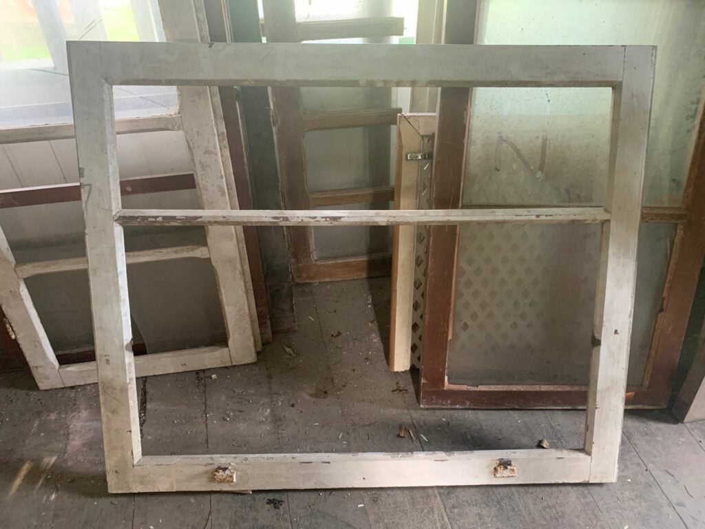 Janela antiga de madeira com pintura branca desgastada aguardando restauração
