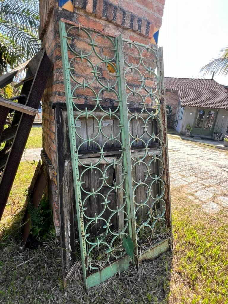Portão antigo de ferro com detalhes circulares e pintura verde desgastada