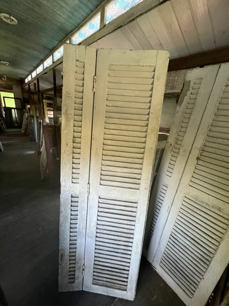 Venezianas antigas de madeira armazenadas no galpão de peças de demolição